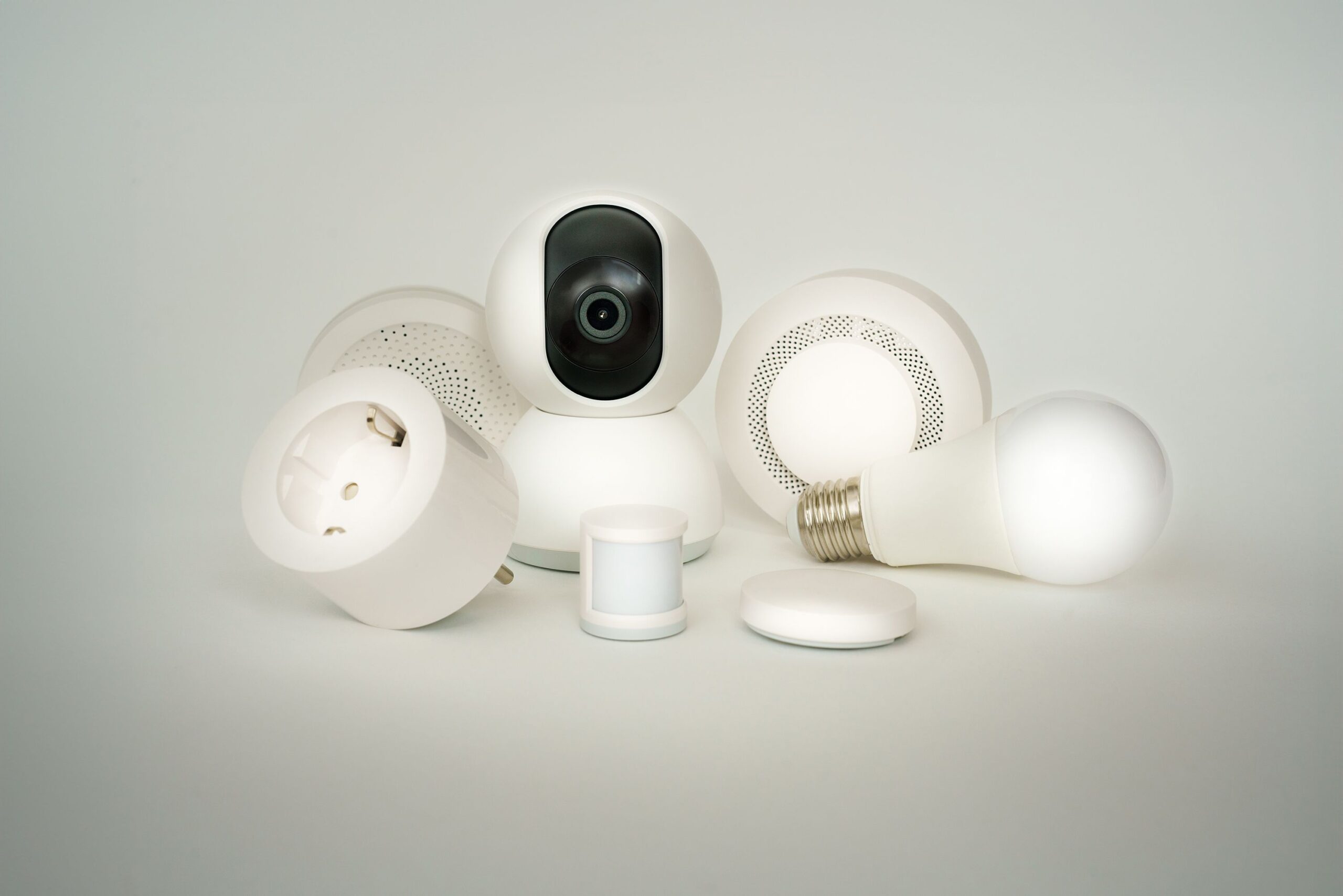 A collection of smart home devices including bulbs, sockets, and cameras on a white backdrop.